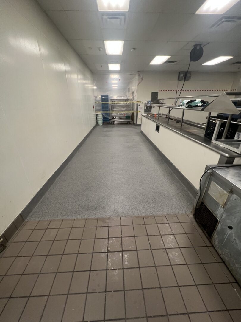 Empty commercial kitchen corridor with stainless counters